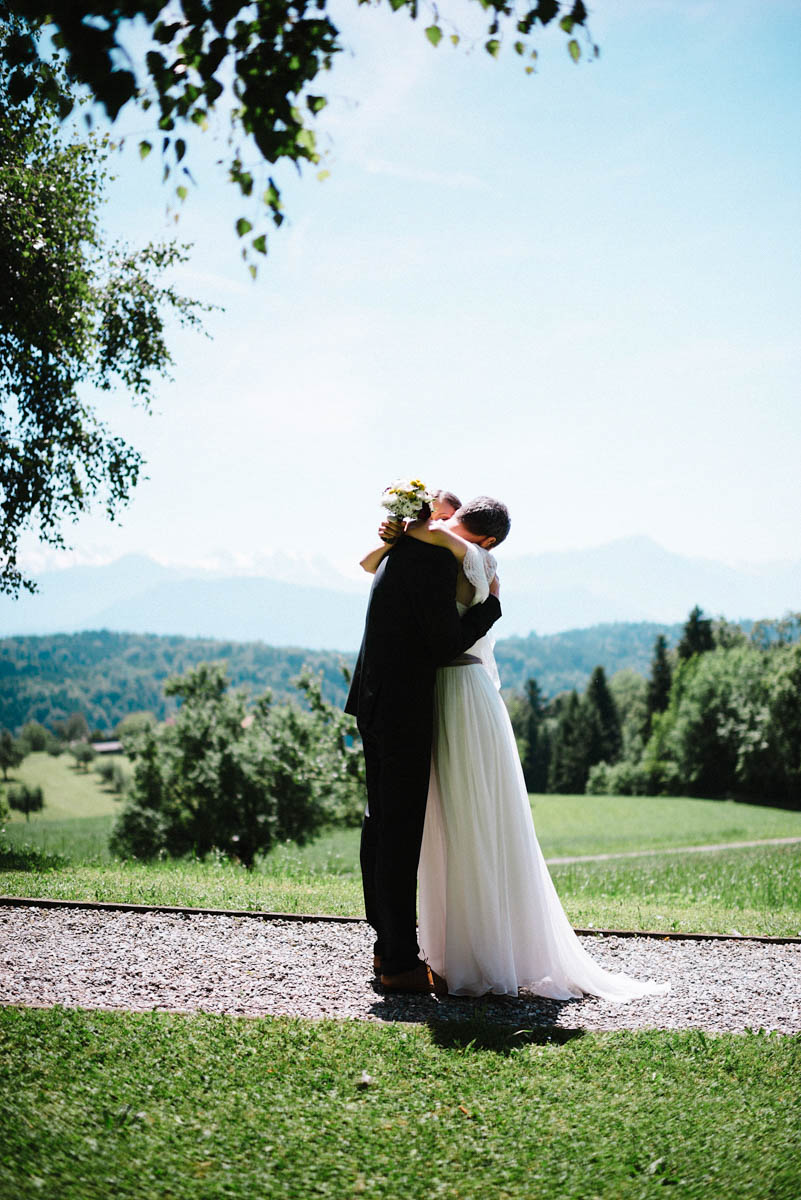 Brautpaar umarmt sich auf der Wiese mit Bergblick nach dem First Look