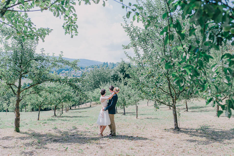 Brautpaar steht auf der Apfelwiese