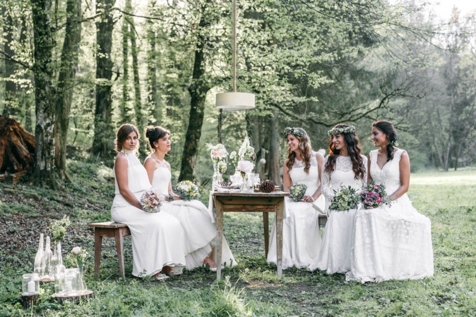 Fünf Bräute mit Boho Brautkleidern am Tisch