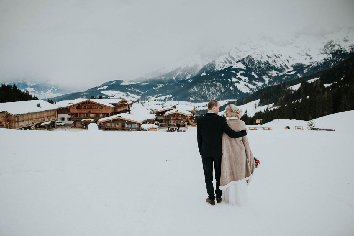 Brautpaar blickt ins verschneite Tal