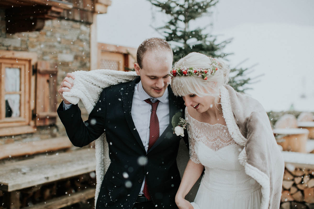 Brautpaar zieht Decke über die Schultern während es schneit