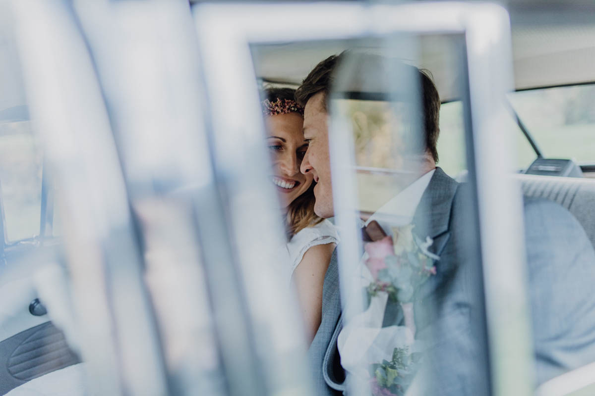 Brautpaar lächelt sich im Hochzeitsauto an
