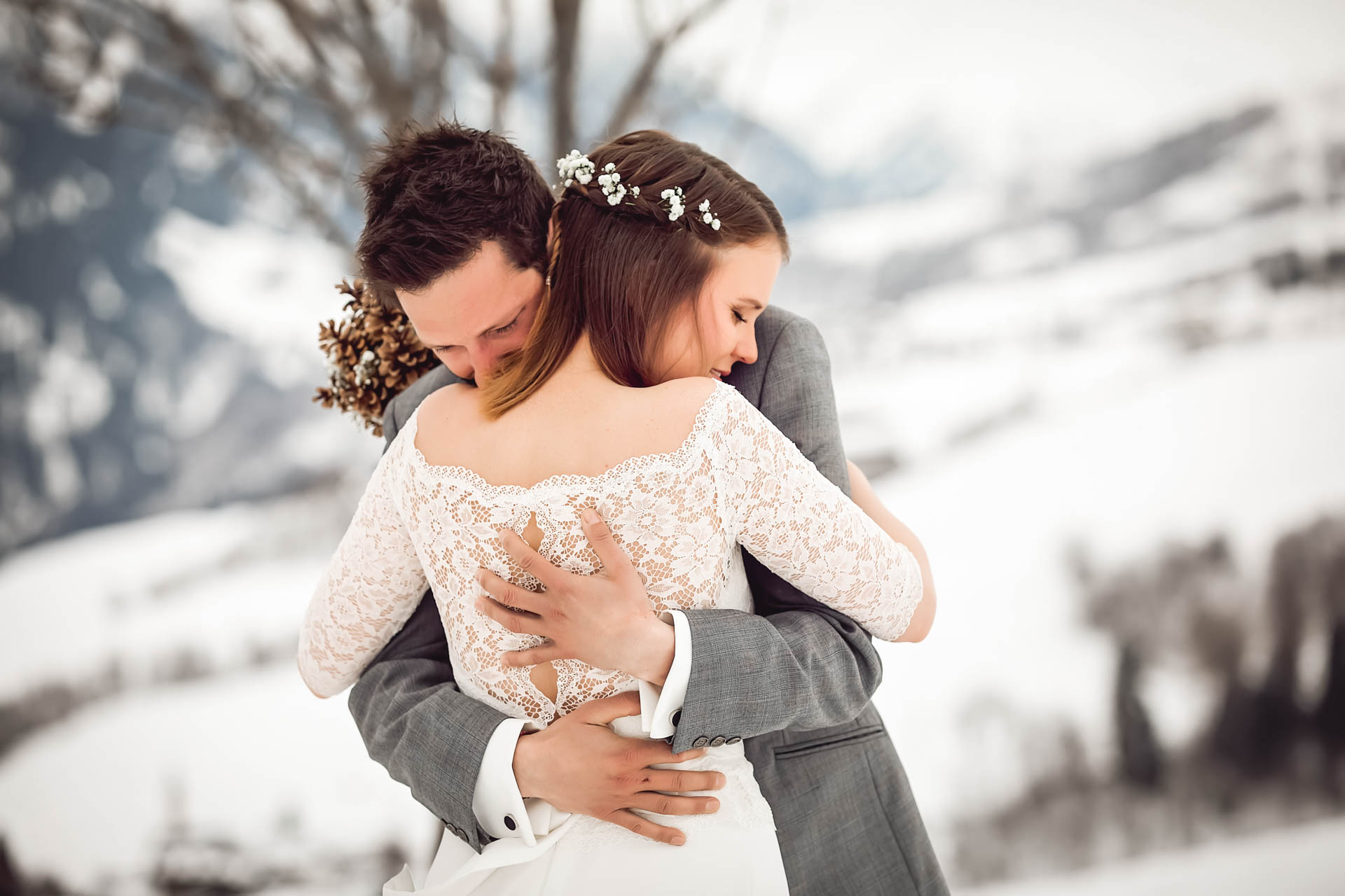 Brautpaar umarmt sich bei Winterhochzeit in den Bergen