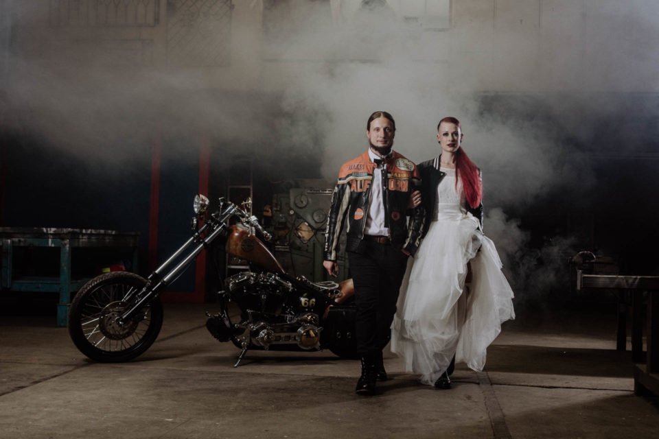 Biker Hochzeit - Brautpaar mit Harley im Hintergrund