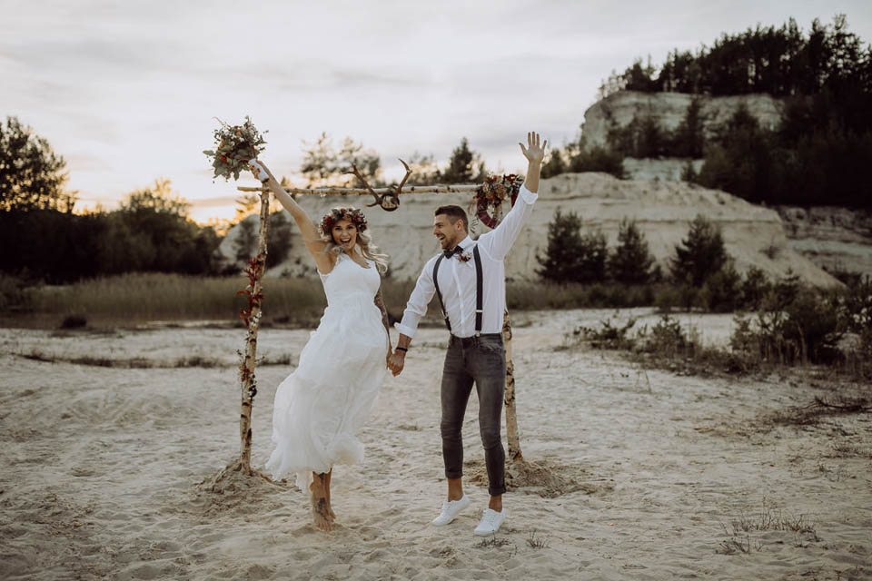 Elopement Hochzeit - Brautpaar springt vor dem Traubogen glücklich in die Luft