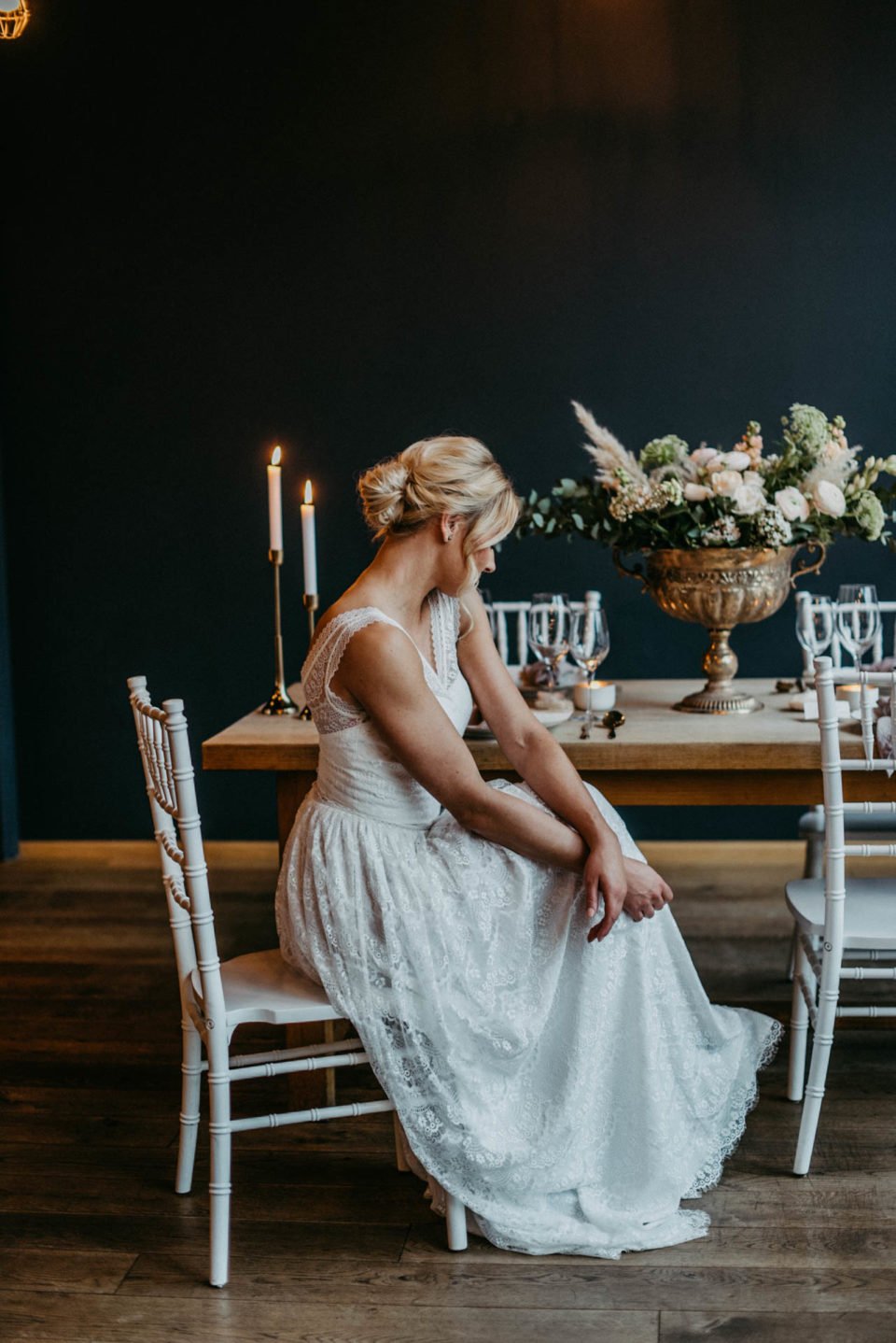 Braut sitzt im Spitzenkleid am Hochzeitstisch