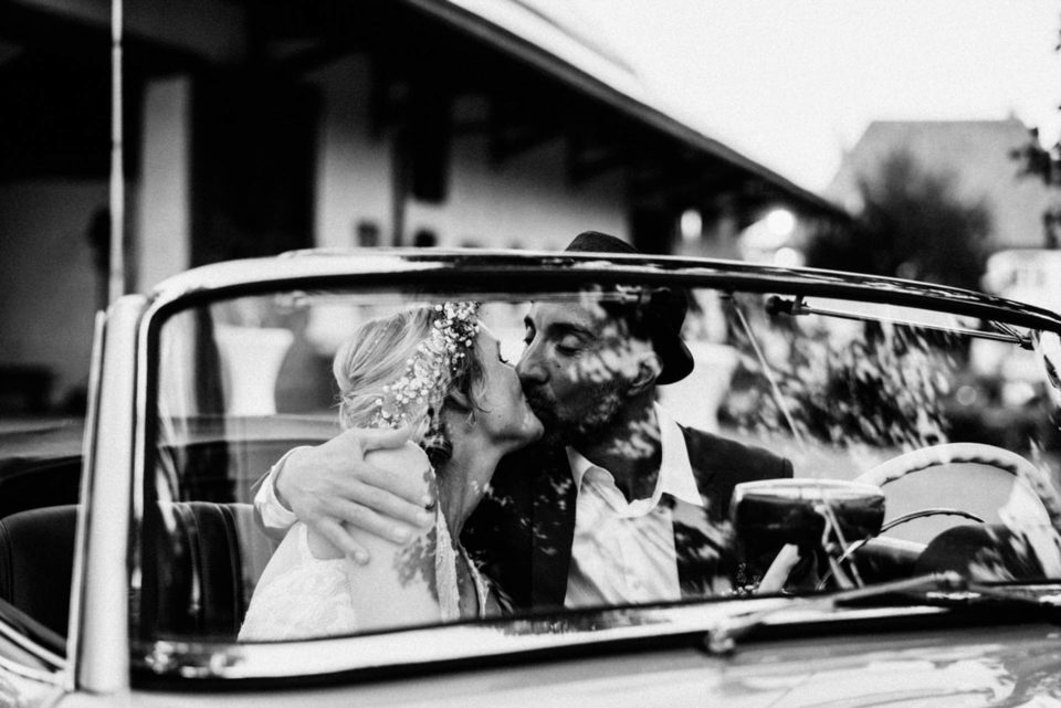 Brautpaar küsst sich im Hochzeitsauto 