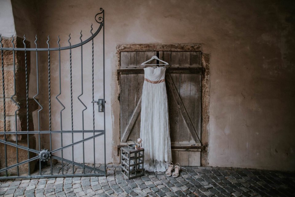 Schulterfreies Vintage Brautkleid hängt vor einer rustikalen Holztüre