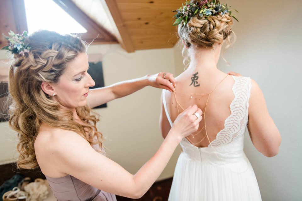 Getting ready - Braut mit rückenfreiem Boho Brautkleid kriegt Boho Rückenkette angelegt