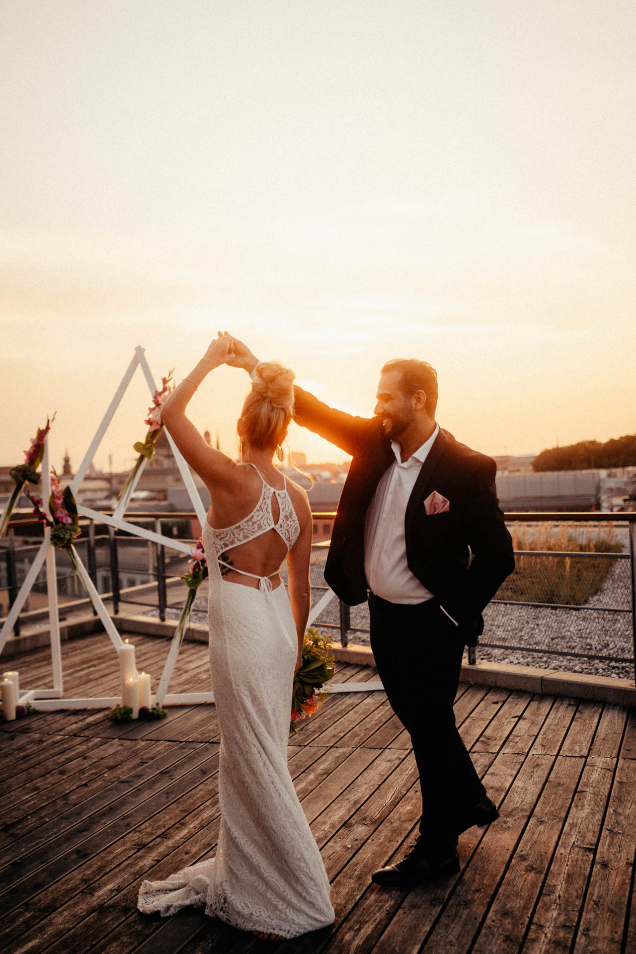 Brautpaar tanzt vor Traumbogen beim Sonnenuntergang 