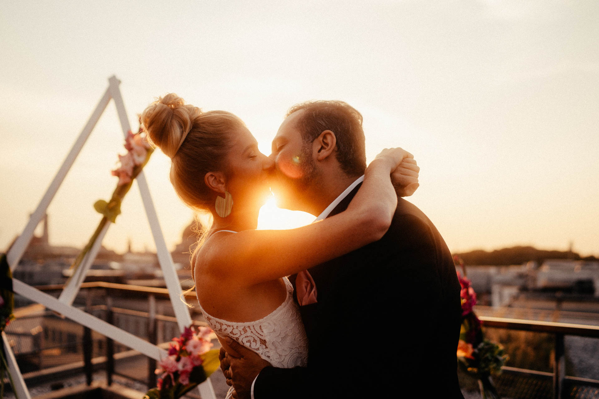 Ehepaar küsst sich nach freier Trauung in München auf der Dachterrasse im Sonnenuntergang