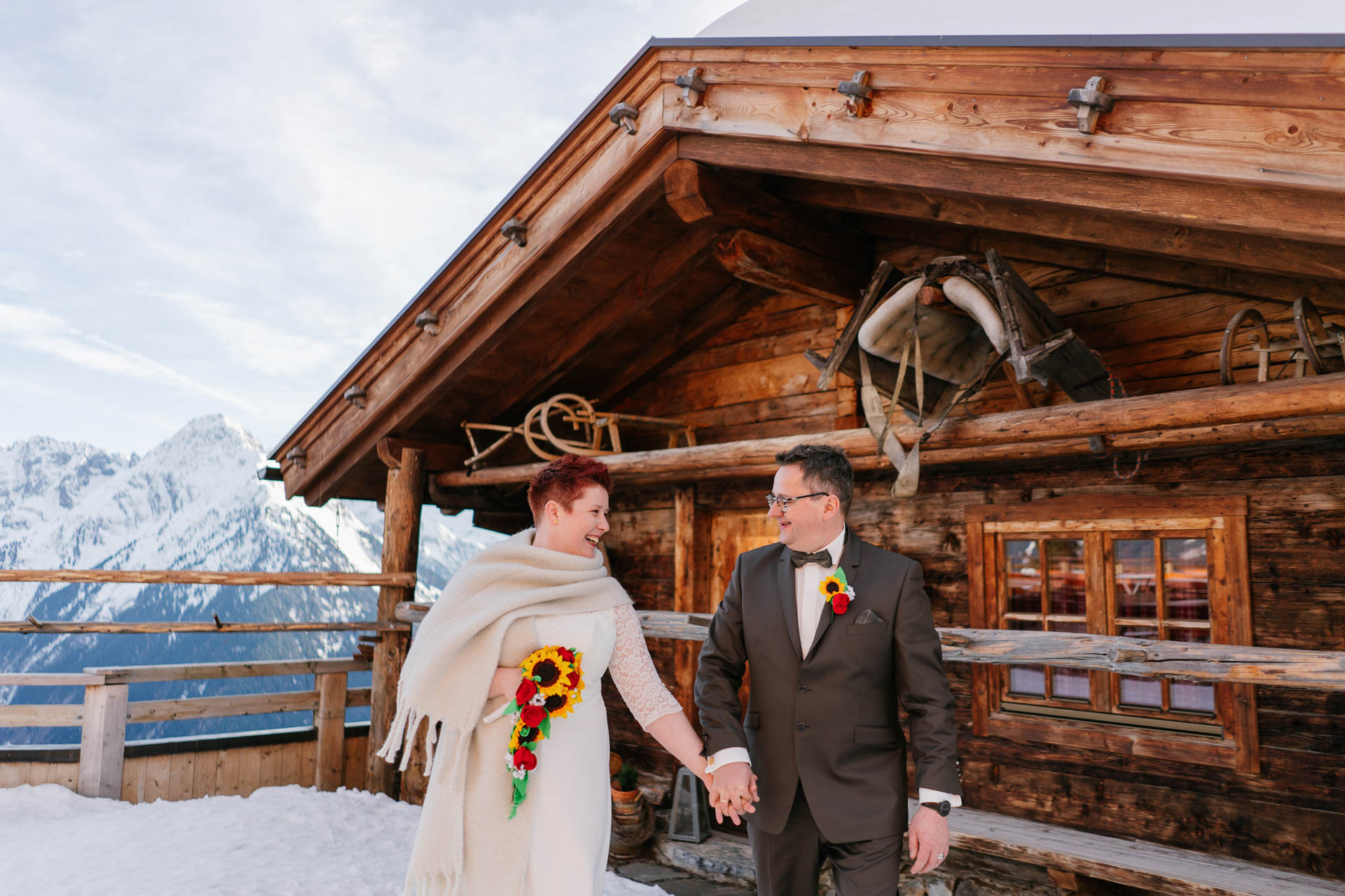 Brautpaar Hand in Hand vor Skihütte im Schnee