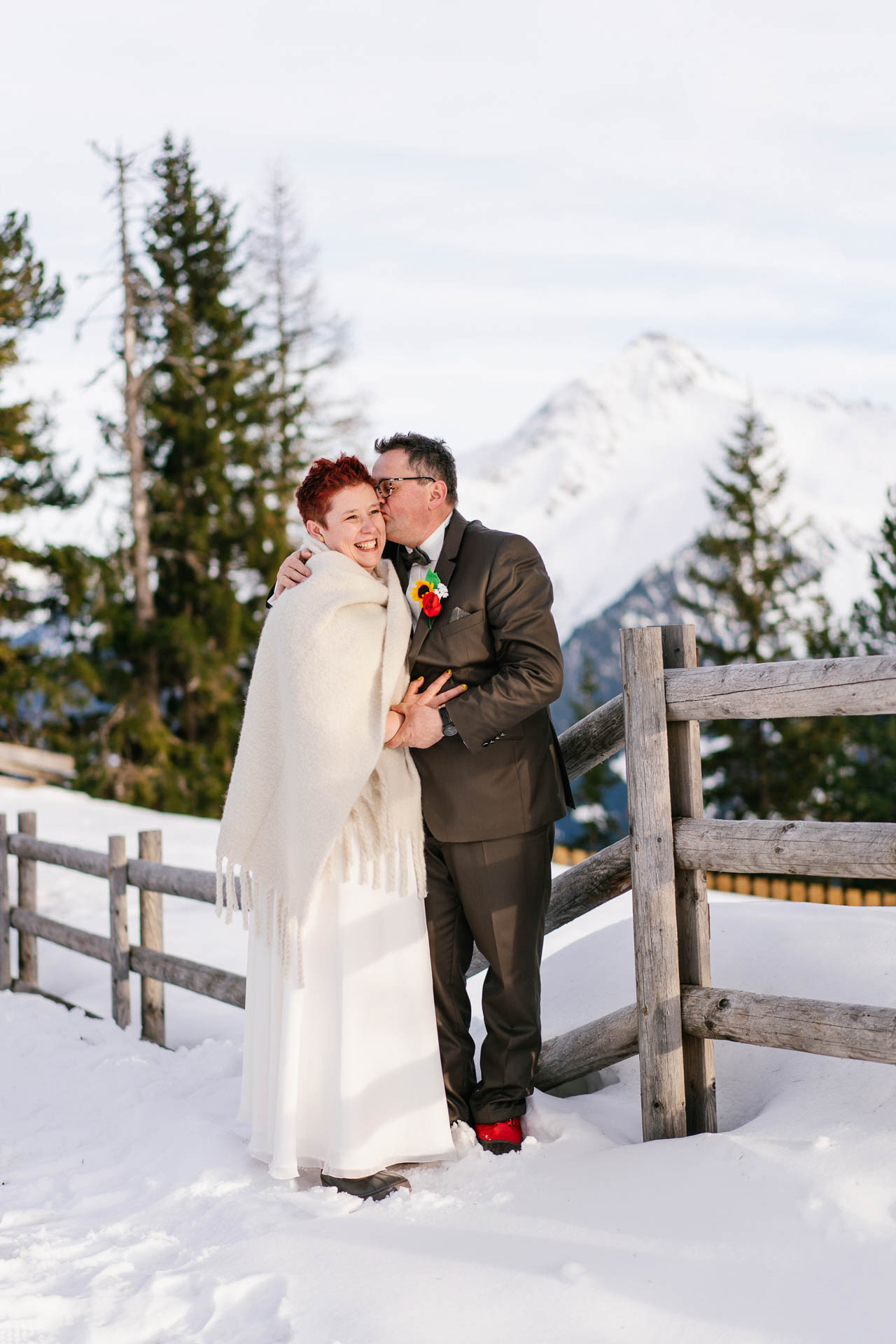 Winterhochzeit im Zillertal, Bräutigam küsst Braut glücklich im Schnee