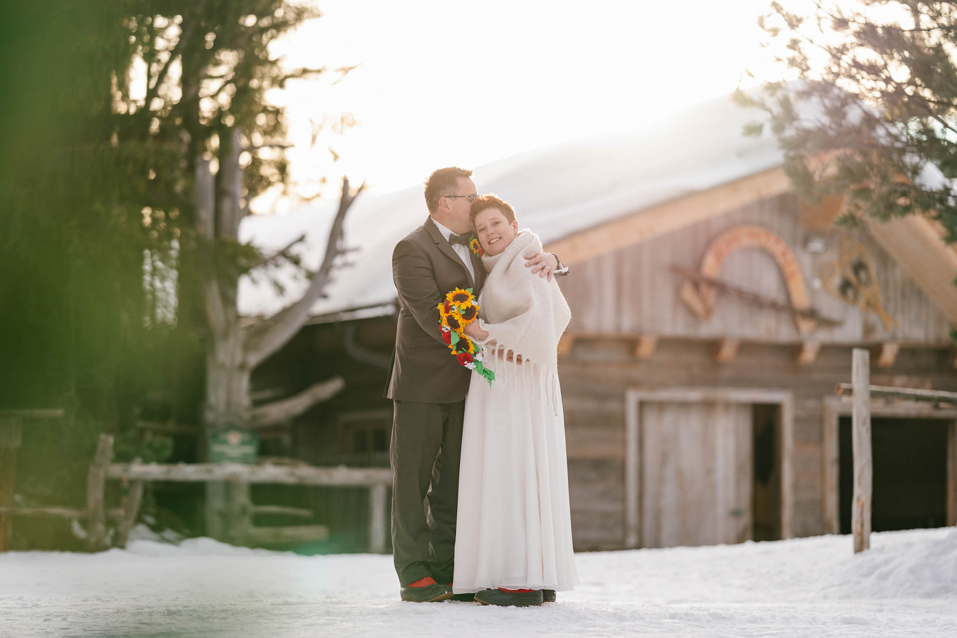Winterhochzeit im Zillertal, Bräutigam umarmt Braut glücklich im Schnee