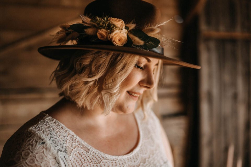 Braut trägt Cowboyhut mit Blumenschmuck