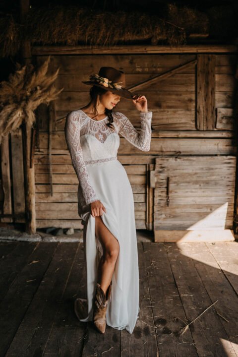 Braut im Countrystyle im Spitzenkleid mit Cowboyhut und Stiefeln