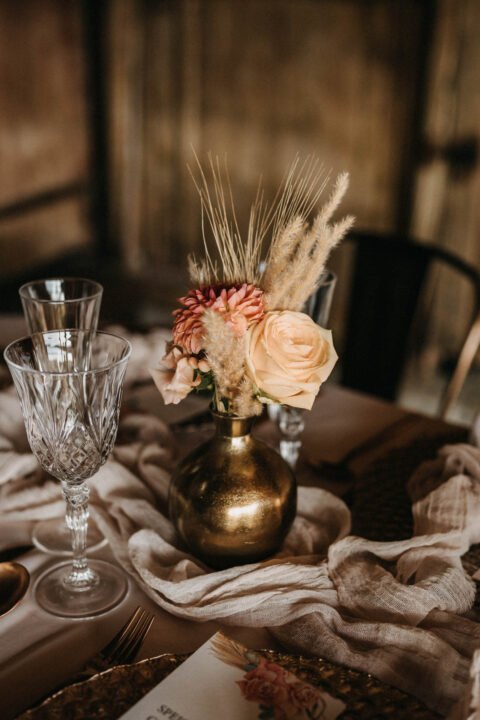 Rosen und Trockenblumen in goldener Vasen als Tischdeko bei Hochzeit