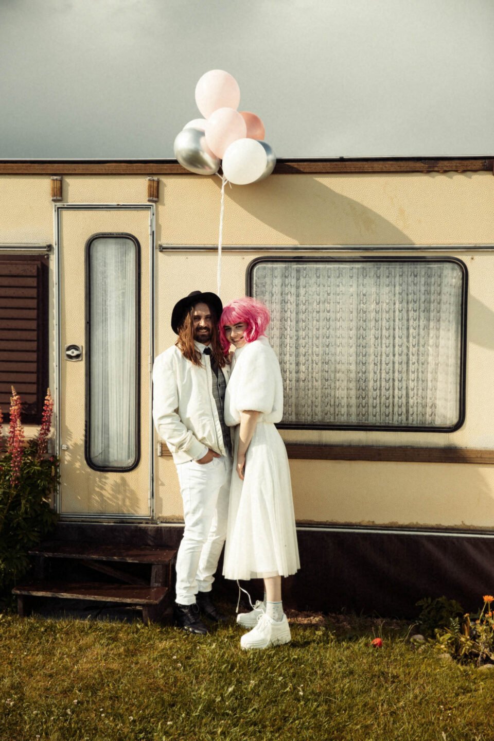 Brautpaar mit Luftballons vorm Wohnwagen