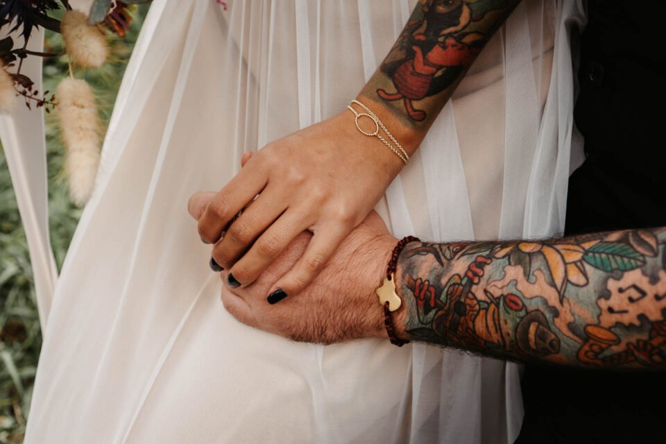 Detailbild beim Händchen halten von Bräutigam und Braut mit Tattoos