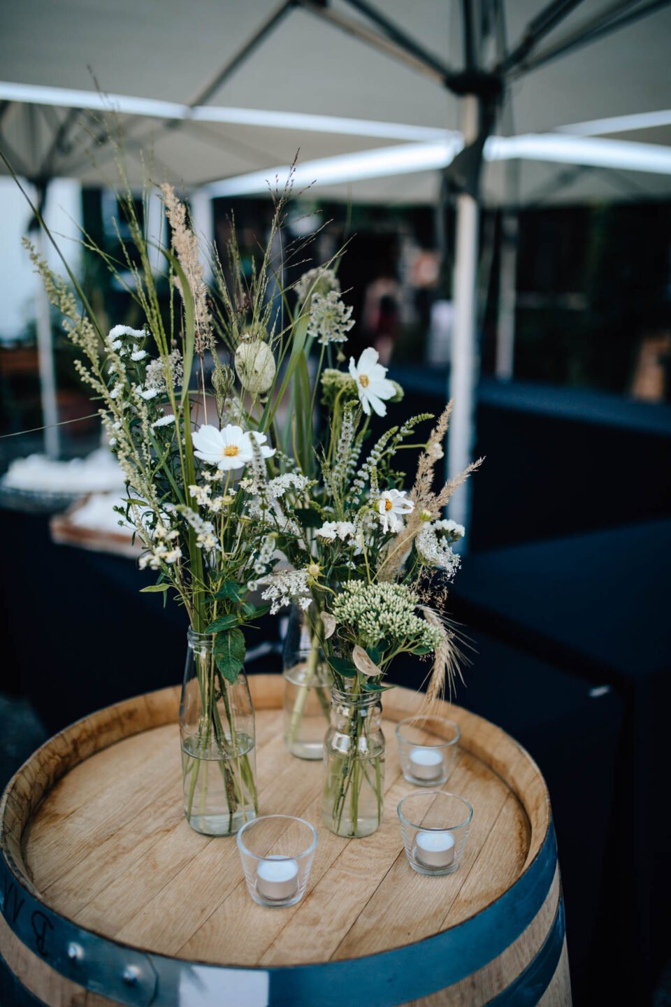 Blumen in Vase auf Weinfaß in der Hochzeitslocation