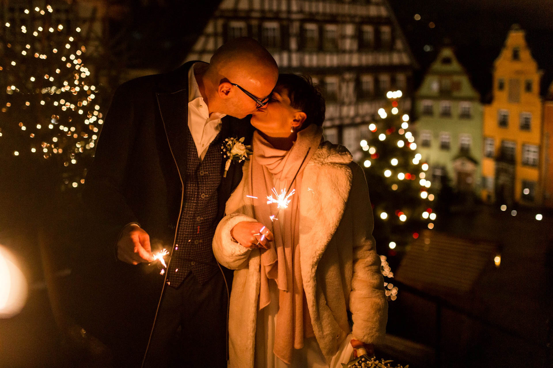 Candle-Light-Hochzeit im Dezember: Brautpaar küsst sich mit Wunderkerzen über der weihnachtlichen Altstadt von Schwäbisch Hall