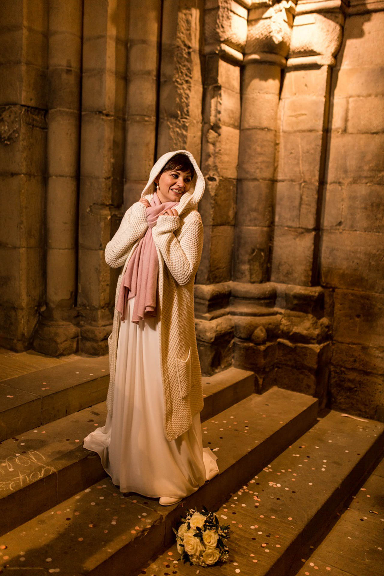 Winterbraut mit Strickjacke und Kapuze auf der Kirchentreppe