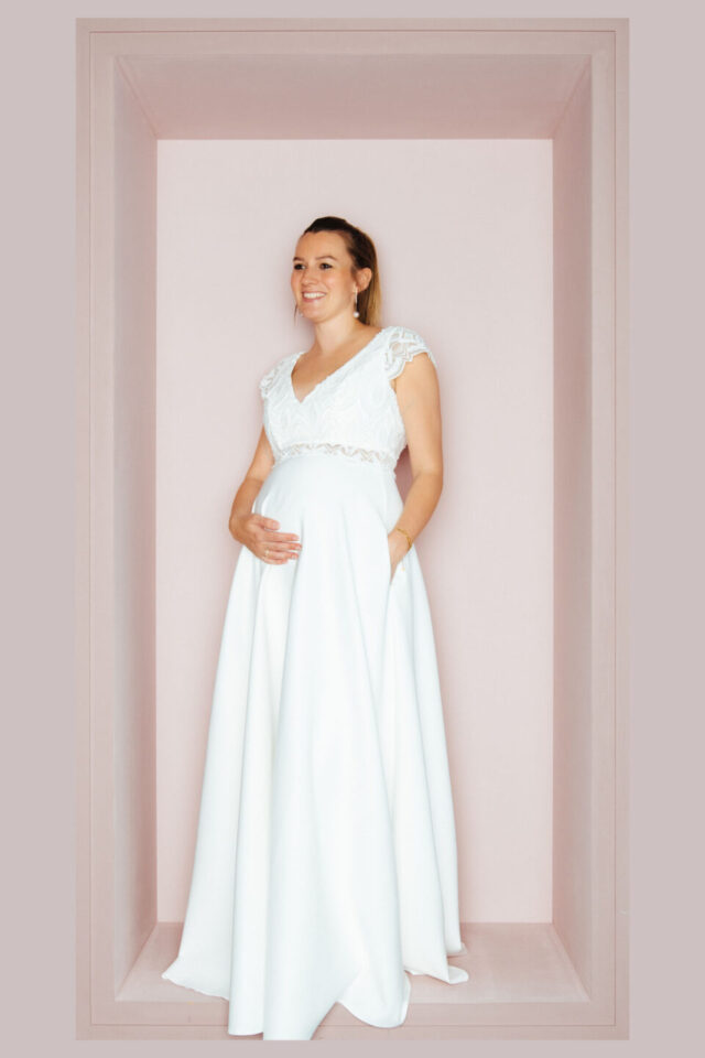 Braut mit Babybauch im Umstandsbrautkleid mit Taschen