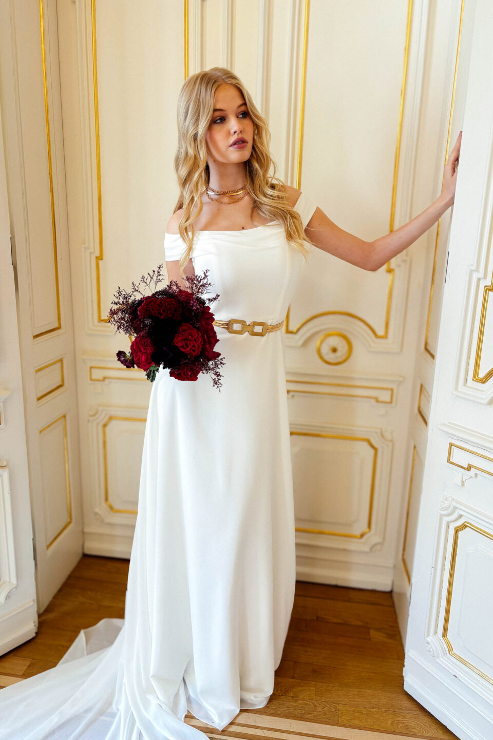 Braut im Chiffon-Brautkleid KUESSdieCARLOW mit goldenem Gürtel und dunkelrotem Brautstrauß