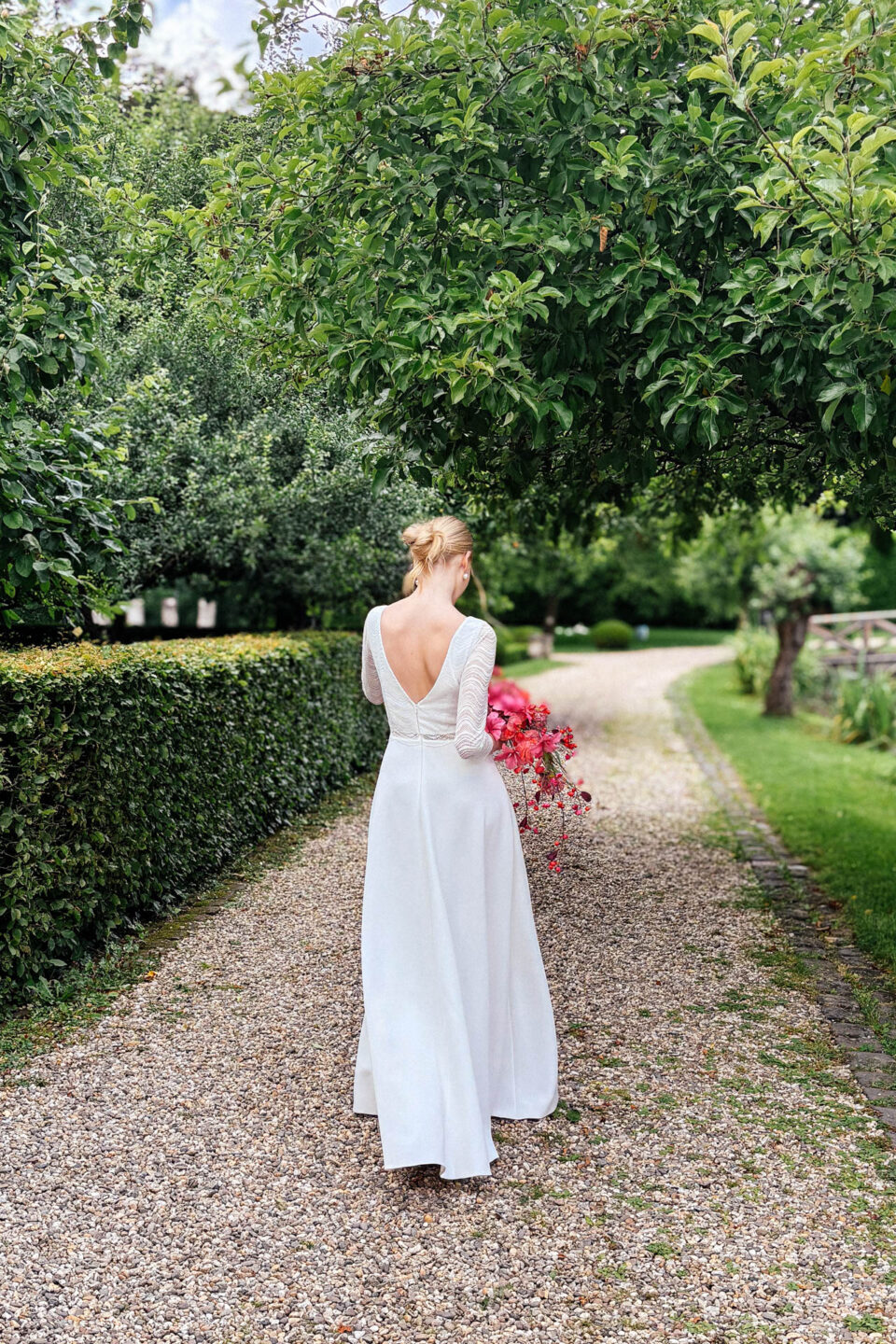 Brautkleid Bobigny Rückenansicht mit V-Rücken und Wellenspitze auf langem Gartenweg