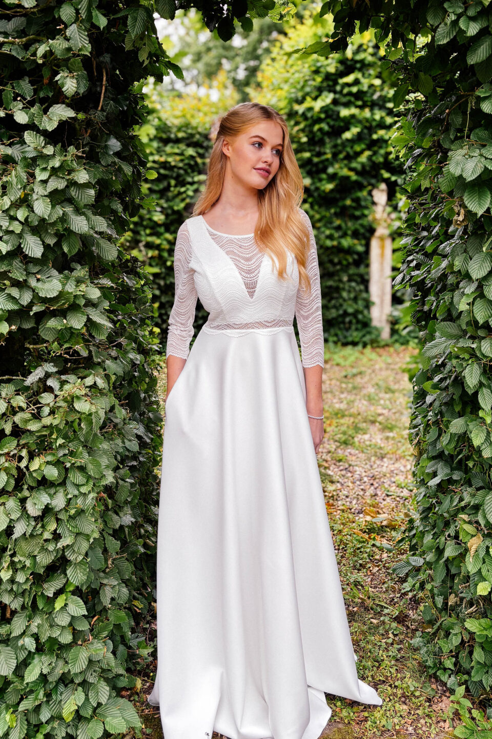 Brautkleid KUESSdieBOBIGNY mit 3/4-Arm aus Wellenspitze unter einem Efeubogen