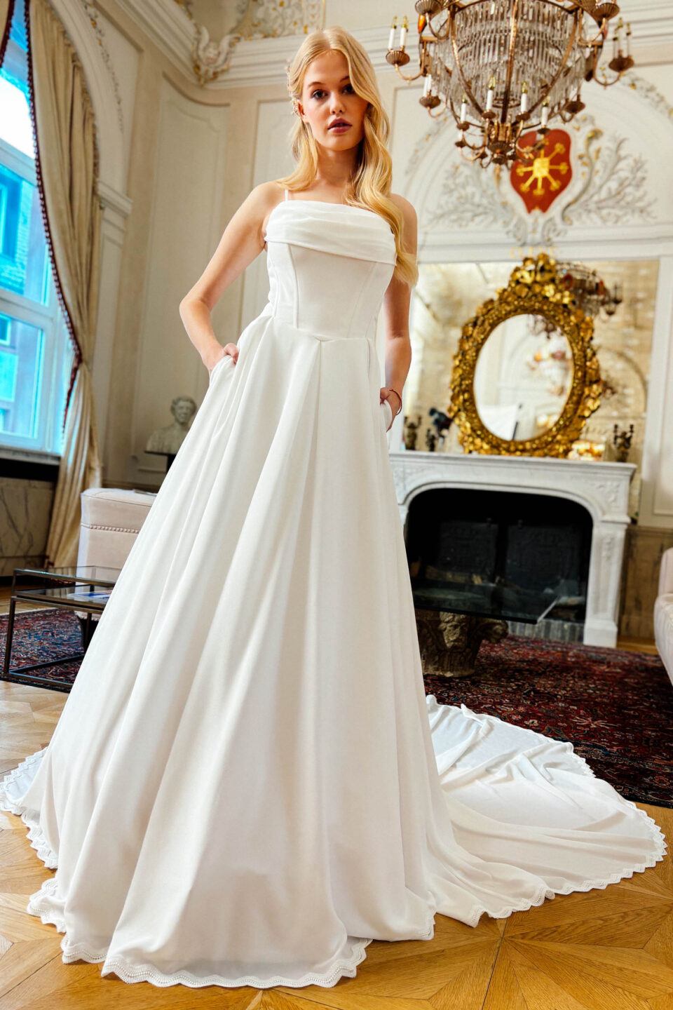 Brautkleid KUESSdieBARNSLEY mit Corsage, Rocktaschen und Schleppe vor dem Kamin